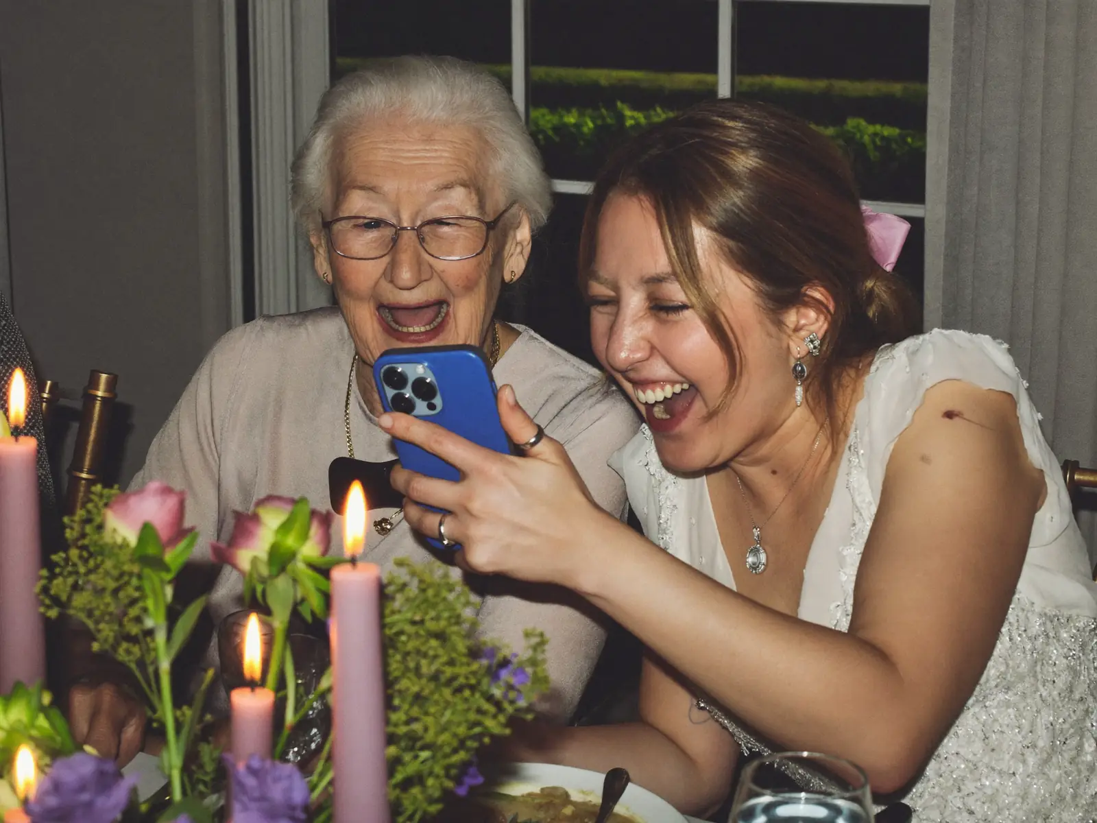 Une grand-mère et sa petite-fille rient devant un téléphone à table